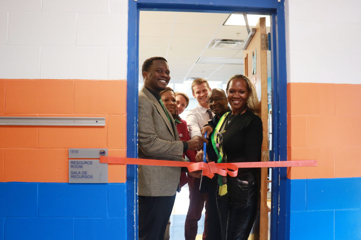 Six individuals including Fayetteville Elementary Principal & community school coordinator cutting ribbon to entrance of their FRC